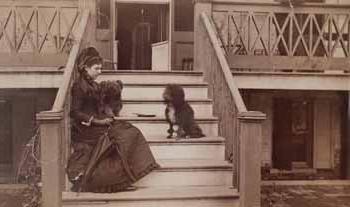 Miss Langdon seated with two dogs on steps of piazza Photograph